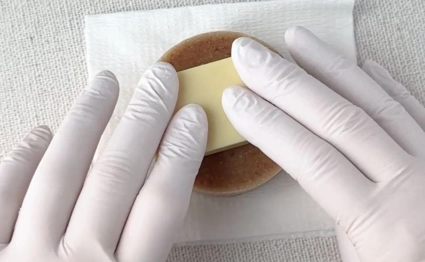 ソープスタンプを上から垂直に置き、面全体へ均一な圧をかけている手元